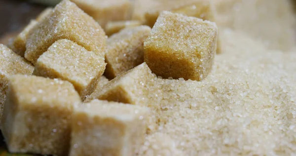 Um tiro macro de uma composição de cana de açúcar, cubos de açúcar e açúcar nos grânulos crus. Conceito: adoçante, natureza, energia, sucos e bebidas . — Fotografia de Stock
