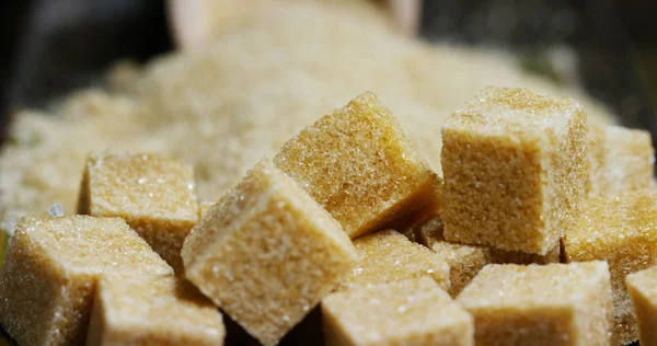 A macro shot of a composition of sugar cane, sugar cubes and sugar in the raw granules. Concept: a sweetener, nature, energy, juices and drinks. — Stock Photo, Image