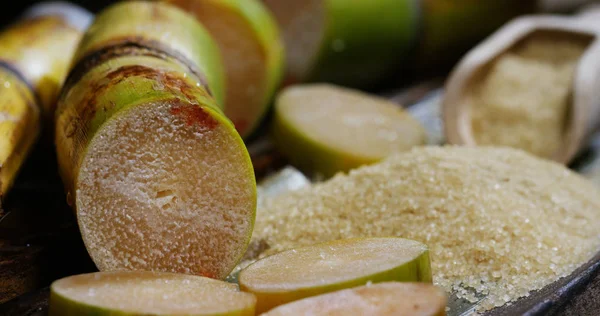 Um tiro macro de uma composição de cana de açúcar, cubos de açúcar e açúcar nos grânulos crus. Conceito: adoçante, natureza, energia, sucos e bebidas . — Fotografia de Stock