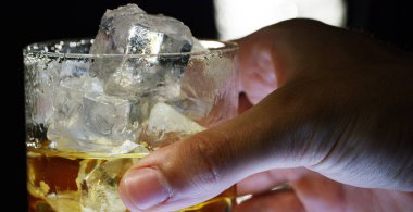 Viski, ağır çekimde buzlu bir bardağa boşaltılmış, makro ateş edilmiş, tahta bir masa ve karanlık bir arka planda. Konsept: alkol, alkol, iyi bir akşam için, alkol sağlığa zarar verir.