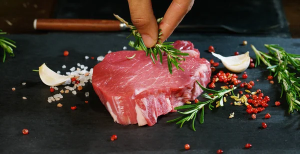 Hermoso filete de carne fresca jugosa en una mesa con sal, romero, ajo y tomate sobre un fondo negro, vista superior. Concepto: productos frescos y naturales, productos biológicos, productos cárnicos, orgánicos, nutrición . —  Fotos de Stock