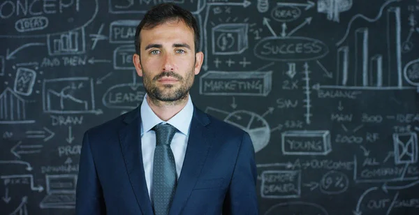 Retrato de um homem de negócios, um professor de marketing, desenha um gráfico de sucesso em uma placa preta, em um fundo preto. O conceito: crescimento da carreira, gráfico de crescimento, homem de sucesso, marketing, ideias, finanças . — Fotografia de Stock