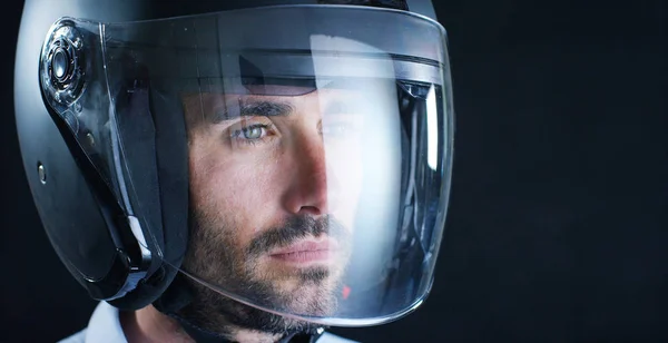 Portret van een prof-renner of de motorrijder, in een beschermende zwarte helm, op een zwarte achtergrond. Concept: bestuurder, station, snelheid, bescherming, beschermend pak, reactie, liefde van extreme sporten. — Stockfoto