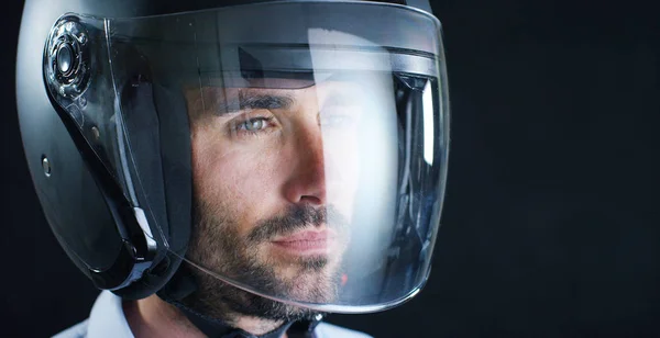 Portret van een prof-renner of de motorrijder, in een beschermende zwarte helm, op een zwarte achtergrond. Concept: bestuurder, station, snelheid, bescherming, beschermend pak, reactie, liefde van extreme sporten. — Stockfoto