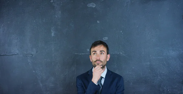 Portrait of a beautiful business man, a marketing teacher, thinking about new ideas and strategies, on a black background. Concept: career growth, growth chart, successful man, marketing, ideas. — Stock Photo, Image