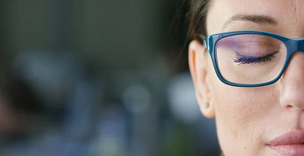 Retrato de una hermosa chica con gafas, ojos cerrados, primer plano, sobre un fondo borroso. Concepto: hermosos ojos, hermosa sonrisa, visión, piel perfecta . — Foto de Stock