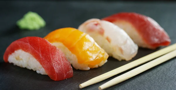 Macro-opname van sushi, sashimi, uramaki en nighiri. typisch Japans gerecht bestaande uit rijst, zalm of tonijn, garnalen en vis eieren gedrenkt in soja. Concept: Sushi, Japans restaurant, oosterse traditie. — Stockfoto