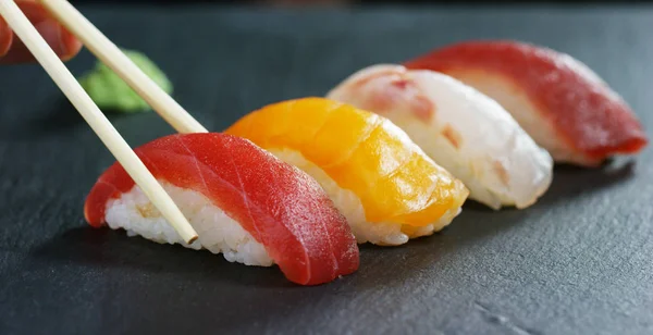 Macro-opname van sushi, sashimi, uramaki en nighiri. typisch Japans gerecht bestaande uit rijst, zalm of tonijn, garnalen en vis eieren gedrenkt in soja. Concept: Sushi, Japans restaurant, oosterse traditie. — Stockfoto