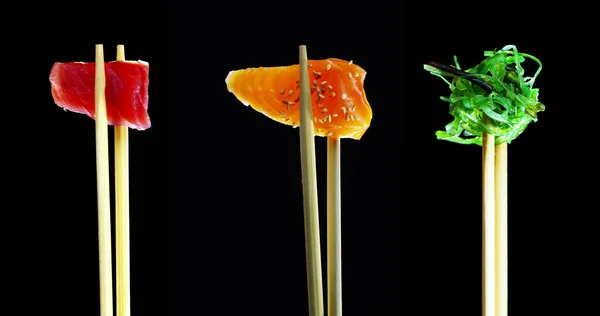 Composição de sushi, sashimi, uramaki e nighiri.typical prato japonês consistindo de arroz, salmão, atum, camarão e ovos de peixe em um fundo preto.Conceito: restaurante japonês, sushi, tradição oriental — Fotografia de Stock