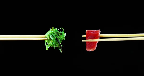 Samenstelling van sushi, sashimi, uramaki en nighiri.typical Japanse schotel bestaande uit rijst, zalm, tonijn, garnalen en vis eieren op een zwarte achtergrond. Concept: Japans restaurant, sushi, oosterse traditie — Stockfoto