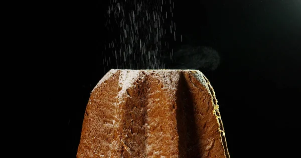 Close up van een Pandoro, een typisch Italiaans gebak gegeten tijdens de kerstvakantie en het nieuwe jaar, de poedersuiker valt in slowmotion op Pandora de kerst magische maken. — Stockfoto