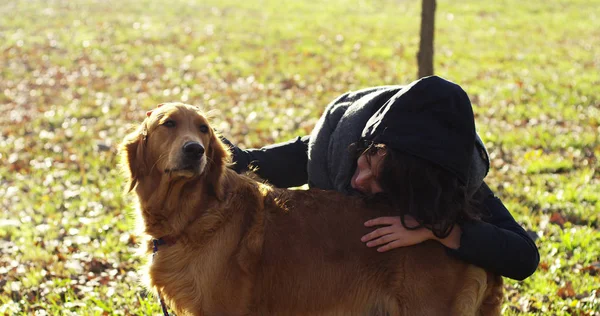 Uma menina abraça, brinca, beija, treina a raça de seu cão Golden Retriever com o pedigree. O cão tem um casaco brilhante e macio. Conceito: raça canina, amor aos animais, suavidade e natureza . — Fotografia de Stock