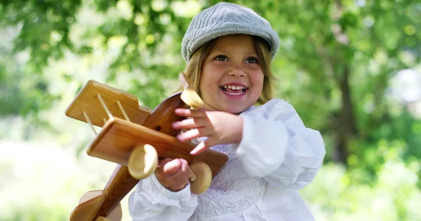 Gadis muda di alam bermain bahagia dengan mainan pesawat kayu, pada hari yang cerah. konsep energi terbarukan, angin, alam, semangat untuk membuat model dan alam dan energi matahari — Stok Foto