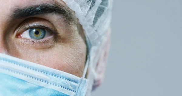 Ritratto ravvicinato di un chirurgo o di un medico con maschera e auricolare pronti per l'operazione in ospedale o in clinica. Il chirurgo sorride sicuro e orgoglioso di sé. Concetto di medicina, ospedali e medici, cure — Foto Stock