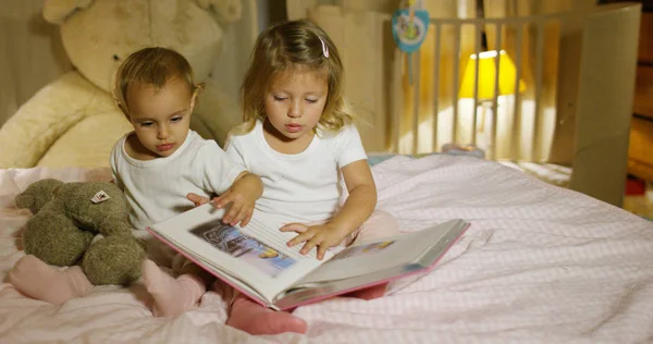 Meninas alegres e felizes lendo na cama de seus pais para jogar. criança feliz. conceito de juventude, alegria e felicidade na infância. conceito de casa segura e proteção . — Fotografia de Stock