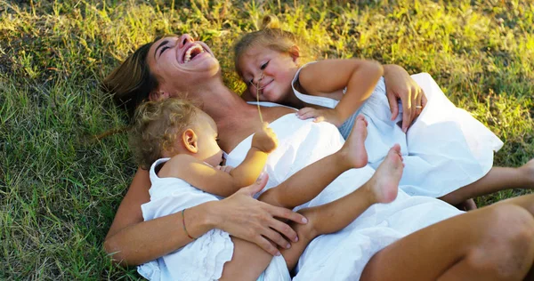 Mother with little girls dressed in a vintage lawn round dence close to a tree in sunset happy little girl in nature. concept of nature and sustainability, connection with nature and the green world. — Stock Photo, Image