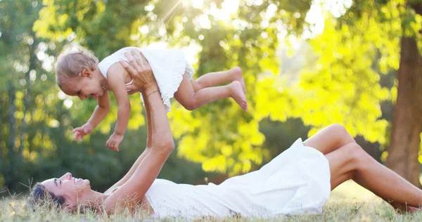 Ecología, madre joven con su adorable niña de dos años jugando al aire libre con amor. concepto de amor familiar por la naturaleza. niños felices con el amor de los padres. concepto de verde y sostenibilidad . — Foto de Stock