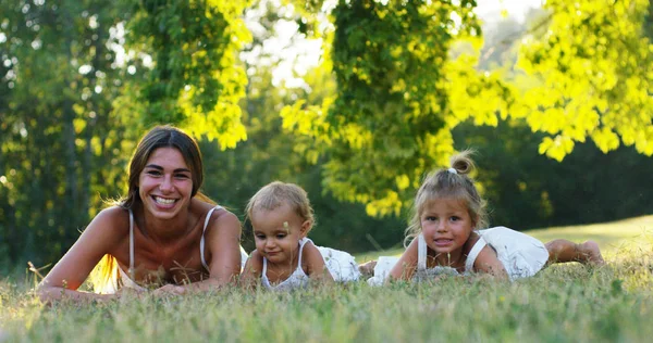 Mother with little girls dressed in a vintage lawn round dence close to a tree in sunset happy little girl in nature. concept of nature and sustainability, connection with nature and the green world. — Stock Photo, Image