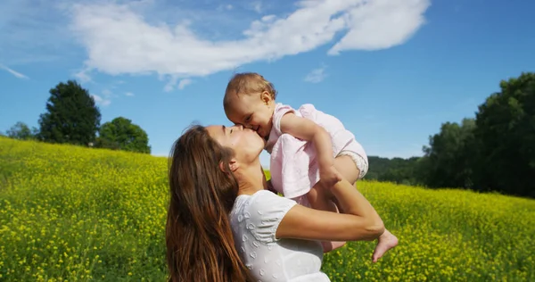 Em um dia ensolarado bonito e feliz, uma mãe e bebê brincam e são felizes imersos na natureza colorida e felicidade, o bebê ri feliz. conceito de felicidade, amor e natureza . — Fotografia de Stock