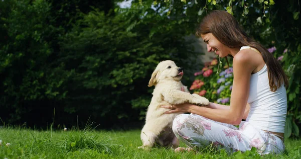 Tendre mère jouant avec un chiot doux golden retriever dans un beau jardin par une journée ensoleillée sur l'herbe. concept d'amitié pour chien et vitamines ou concept de chien sain. bonheur nature animal — Photo