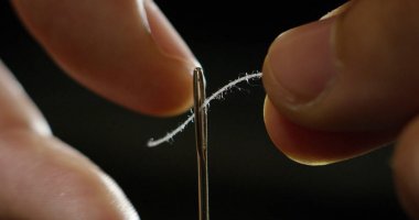 Ağır çekim dikmek iğne ve iplik ile el ile Dikiş dikiş eski geleneğe göre genç bir terzi elin.