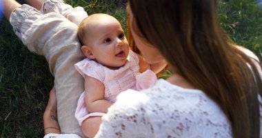 Süper ağır çekim bir şefkatle 4 k bir güneş bağında bir çayırda onun bebek kız öpüşme genç beyaz anne (yakın fişekleri ile)