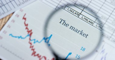 Bir Finansal gazete ve iş planı futuristik grafik ile mali çanta üzerinde bir el bir büyüteç ile geçer. Konsept: Ekonomi, finans, kriz, iş planı, gelecek
