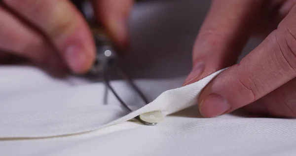 A hand of a young seamstress sewing a white cloth tailoring according to the tradition of tailors. The dressmaker uses perfectly needle and thread to sew traditional concept, sewing, style and fashion — Stock Photo, Image