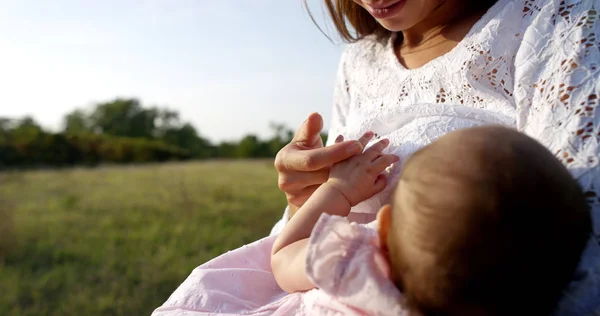 Super slow motion of young Caucasian mother spinning her baby girl e in a meadow of vineyard on a sunny day in 4k (close up with flares)