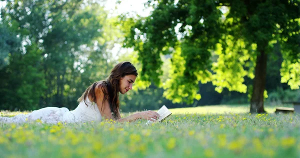 В солнечный день красивая женщина расслабляется в тени дерева, чтобы почитать книгу и расслабиться, книга действительно нравится женщине, которая является любителем литературы и тишины. расслабиться — стоковое фото