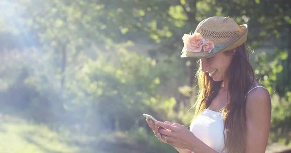 En un día soleado, una hermosa mujer tomando fotos o escribiendo mensajes y usando su teléfono celular, animando sonriendo mientras hace videollamadas con su teléfono inteligente. concepto de conexión conectividad — Foto de Stock