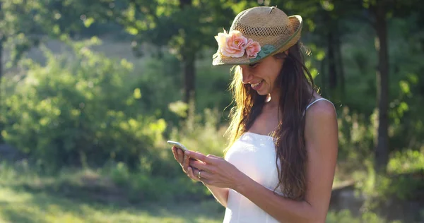 En un día soleado, una hermosa mujer tomando fotos o escribiendo mensajes y usando su teléfono celular, animando sonriendo mientras hace videollamadas con su teléfono inteligente. concepto de conexión conectividad — Foto de Stock