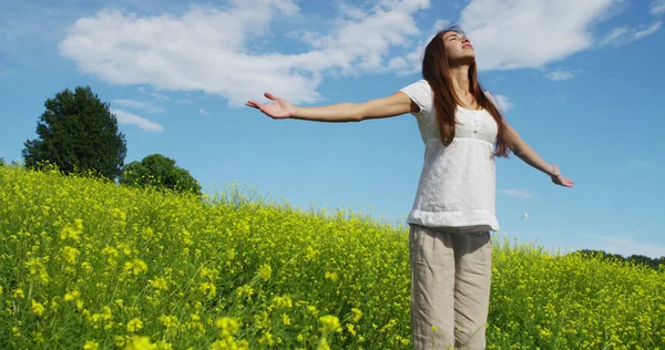 En un hermoso día soleado una mujer es feliz en la naturaleza. concepto de felicidad y naturaleza. una pradera de flores amarillas y el cielo azul. naturaleza colorida — Foto de Stock