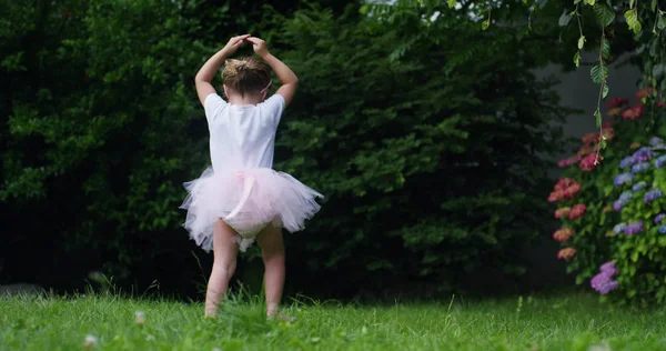 En un soleado día de primavera una niña vestida como una bailarina de ballet dando vueltas por el jardín y sonriendo feliz — Foto de Stock