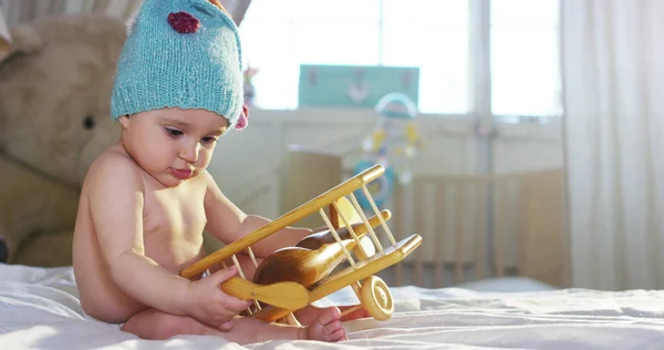 Kleines Mädchen, das mit farbigen Holzwürfeln auf dem Bett der Eltern spielt. Das Kind ist neugierig und erkundet neues buntes Spielzeug. Konzept der Neugier und Kinder glücklich und gesund — Stockfoto