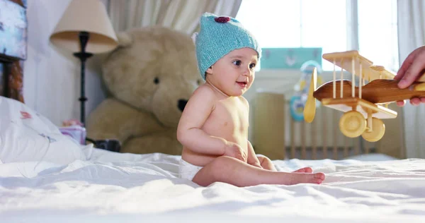 Little girl playing with colored wooden cubes on the bed of the parents . the child is curious and explores new colorful toys . concept of curiosity and children happy and healthy — Stock Photo, Image