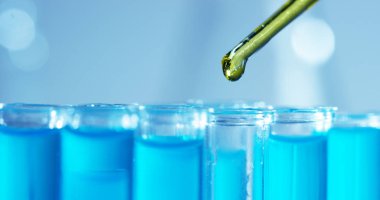 Bir laboratuarda, pipetli bir bilim adamı test tüplerindeki DNA ve molekülleri ayırmak için renkli bir sıvıyı analiz eder. Konsept: araştırma, biyokimya, doğa, ilaç