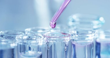 Bir laboratuarda, pipetli bir bilim adamı test tüplerindeki DNA ve molekülleri ayırmak için renkli bir sıvıyı analiz eder. Konsept: araştırma, biyokimya, doğa, ilaç