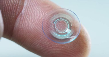 Makro çekim bir kontakt lens teknolojisi ile gözleri ve artış diyoptriden daha iyi görmek için küçük parça tutan bir parmak. Konsept: göz muayenesinde, optik, üstün teknoloji