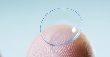 Makro çekim bir kontakt lens teknolojisi ile gözleri ve artış diyoptriden daha iyi görmek için küçük parça tutan bir parmak. Konsept: göz muayenesinde, optik, üstün teknoloji