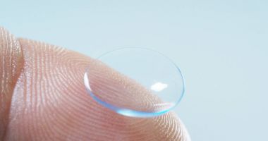 Makro çekim bir kontakt lens teknolojisi ile gözleri ve artış diyoptriden daha iyi görmek için küçük parça tutan bir parmak. Konsept: göz muayenesinde, optik, üstün teknoloji