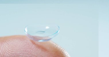 Makro çekim bir kontakt lens teknolojisi ile gözleri ve artış diyoptriden daha iyi görmek için küçük parça tutan bir parmak. Konsept: göz muayenesinde, optik, üstün teknoloji