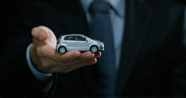 Bir takım elbise ve kravat, giymiş bir adam küçük bir otomatik gösterir. Konsept: araba sigortası, mekanik, Finansal Kiralama, satın yeni ve kullanılmış otomobil ve ortak garajlar.