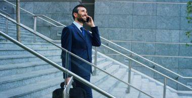 Yürüyen merdiven üzerinde bir işadamı telefon cevaplar, iletileri ve gülümsüyor için belgili tanımlık güzel iş haber gönder. Konsept: teknoloji, telefon, iş gezileri, iş.
