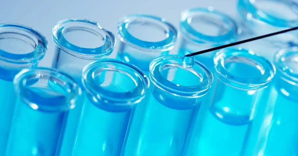 У лабораторії вчений з трубкою аналізує кольорову рідину, щоб отримати ДНК і молекули в пробірці. Концепція: дослідження, біохімія, природа, фармацевтична медицина — стокове фото