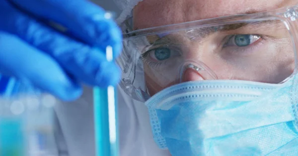 En un laboratorio, un científico con una pipeta analiza un líquido de color para extraer el ADN y las moléculas en los tubos de ensayo. Concepto: investigación, bioquímica, naturaleza, medicina farmacéutica —  Fotos de Stock