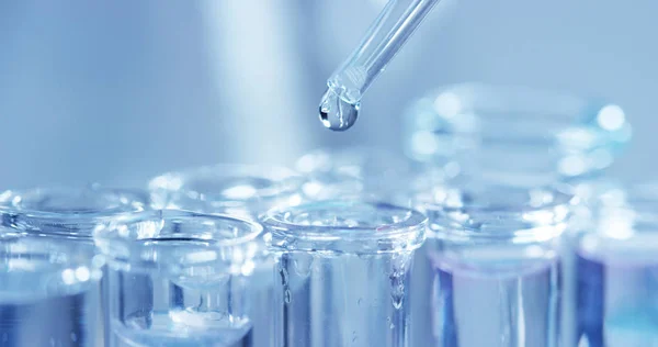 Σε ένα εργαστήριο, ένας επιστήμονας με πιπέτα αναλύει ένα χρωματιστό υγρό για να εξαγάγει το DNA και τα μόρια στους δοκιμαστικούς σωλήνες. Έννοια: έρευνα, βιοχημεία, φύση, φαρμακευτική ιατρική — Φωτογραφία Αρχείου