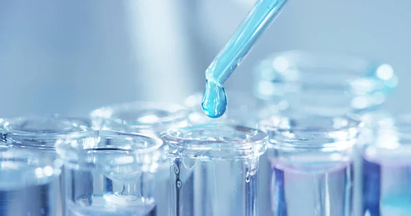 In een laboratorium analyseert een wetenschapper met een pipet een gekleurde vloeistof om het DNA en de moleculen in de reageerbuizen te extraheren. Onderwerp: onderzoek, biochemie, natuur, farmaceutische geneeskunde — Stockfoto