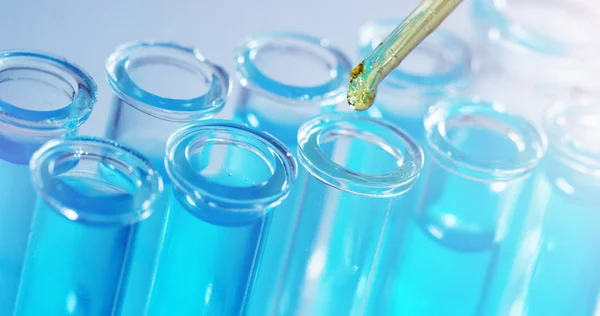 In een laboratorium analyseert een wetenschapper met een pipet een gekleurde vloeistof om het DNA en de moleculen in de reageerbuizen te extraheren. Onderwerp: onderzoek, biochemie, natuur, farmaceutische geneeskunde — Stockfoto