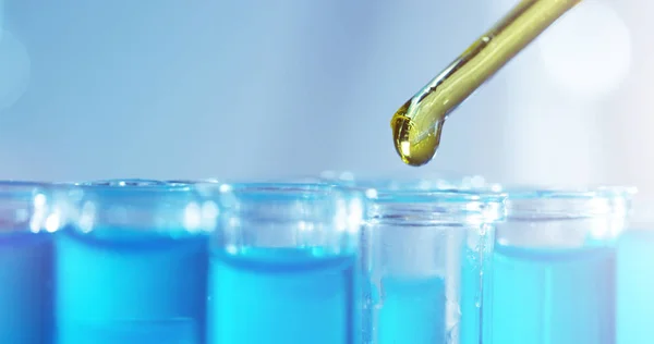 V laboratoři vědec s pipetou analyzuje barevnou tekutinu, aby extrahoval DNA a molekuly ve zkumavkách. Koncept: výzkum, biochemie, příroda, farmaceutická medicína — Stock fotografie